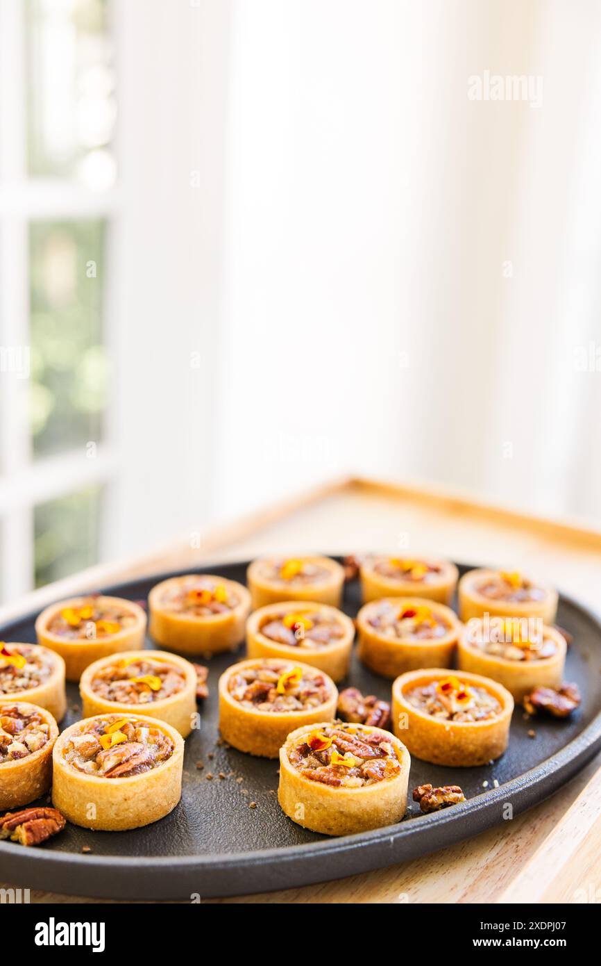 Assiette de mini tartes aux noix de pécan dans un cadre lumineux et élégant Banque D'Images