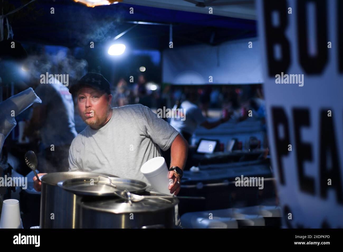Vendeur à un marché nocturne servant des cacahuètes bouillies chaudes avec un surpr Banque D'Images