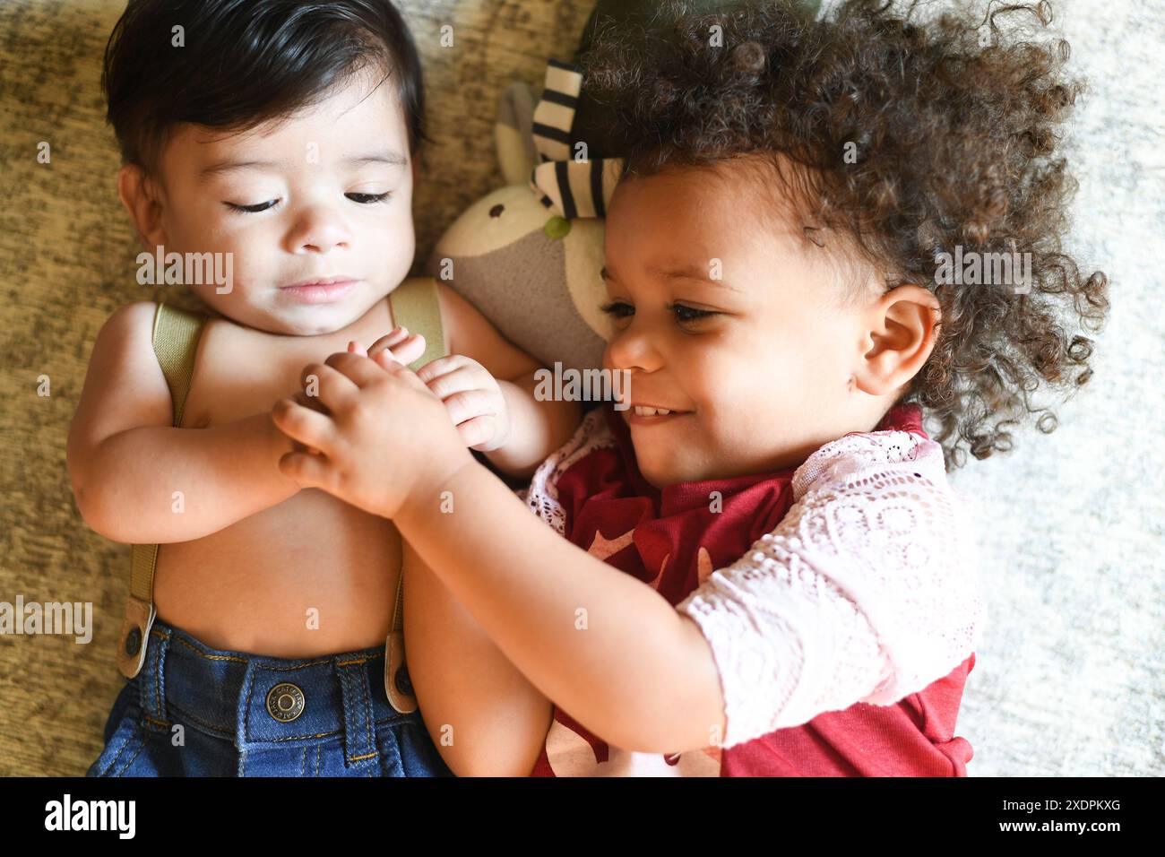 Deux enfants couchés ensemble, souriant et se tenant la main. Banque D'Images