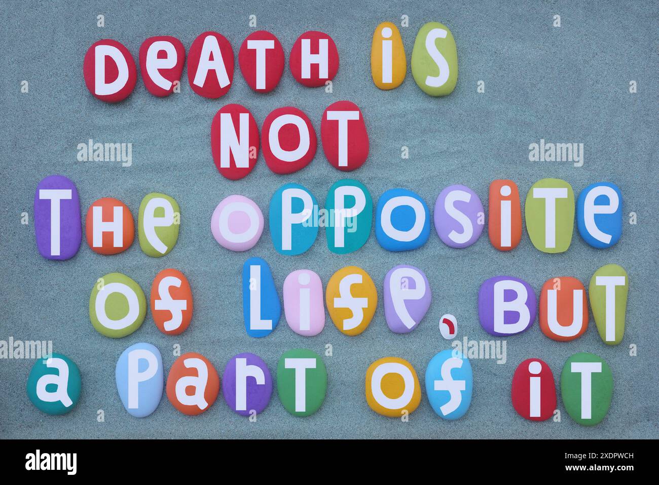 La mort n'est pas l'opposé de la vie, mais une partie de celle-ci, citation de vie composée de lettres de pierre multicolores peintes à la main sur du sable vert Banque D'Images