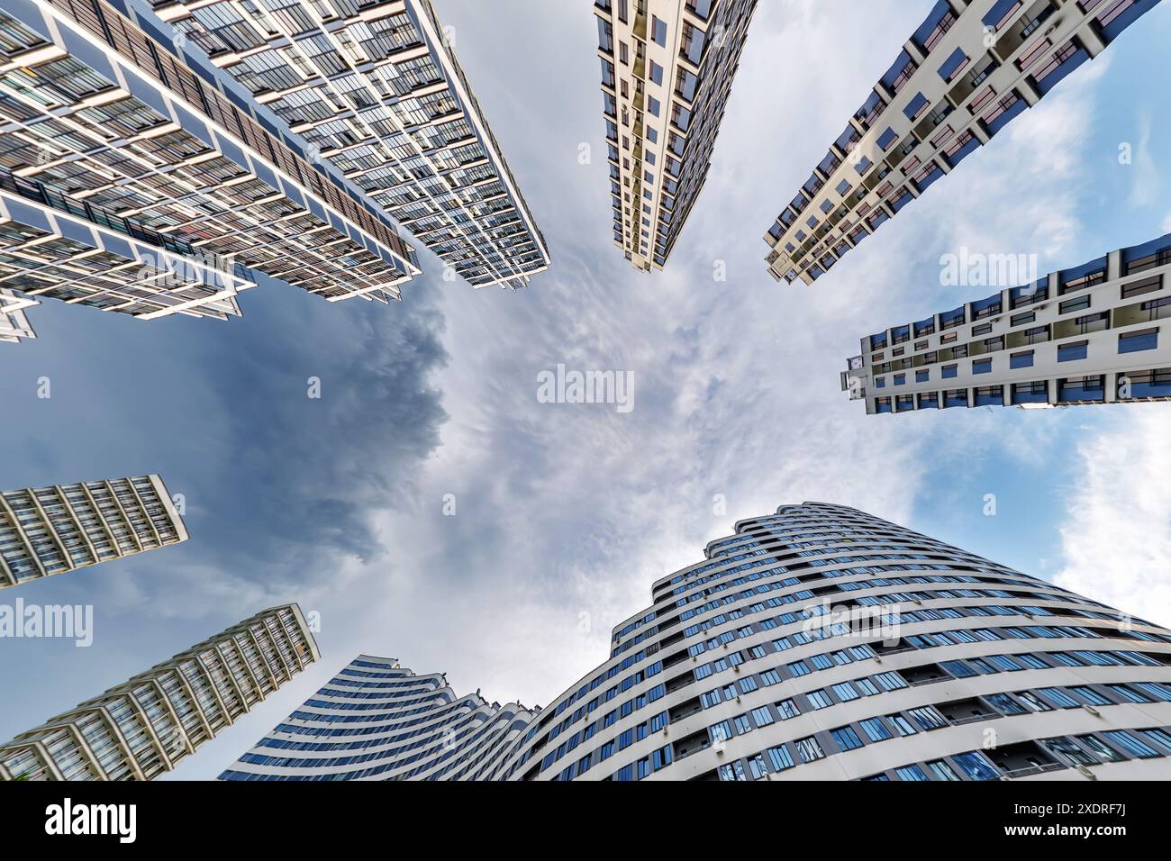 vue d'en bas dans le ciel orageux avec des nuages sombres de grand complexe résidentiel de gratte-ciel moderne Banque D'Images