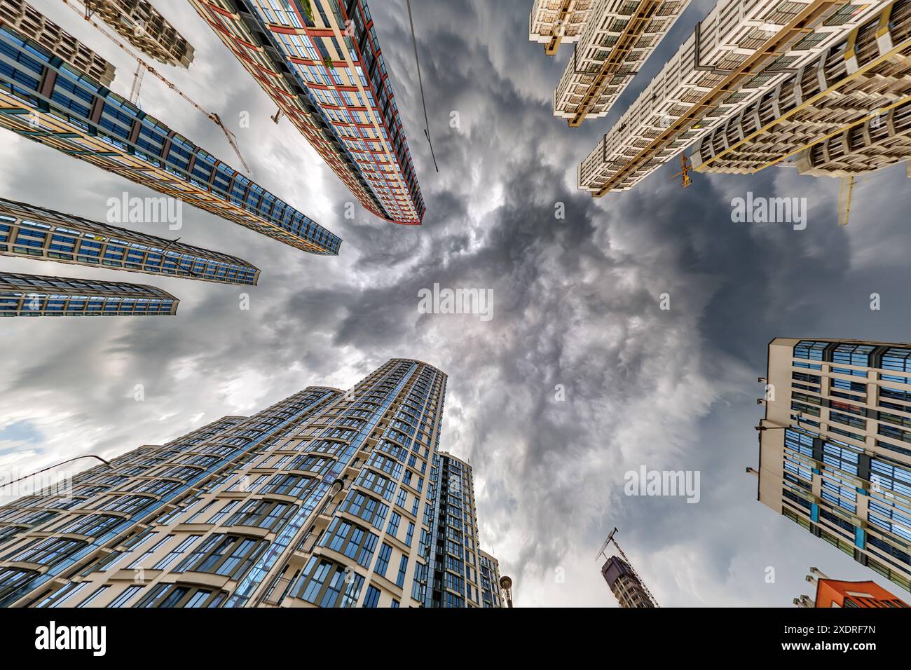 vue d'en bas dans le ciel orageux avec des nuages sombres de grand complexe résidentiel de gratte-ciel moderne Banque D'Images