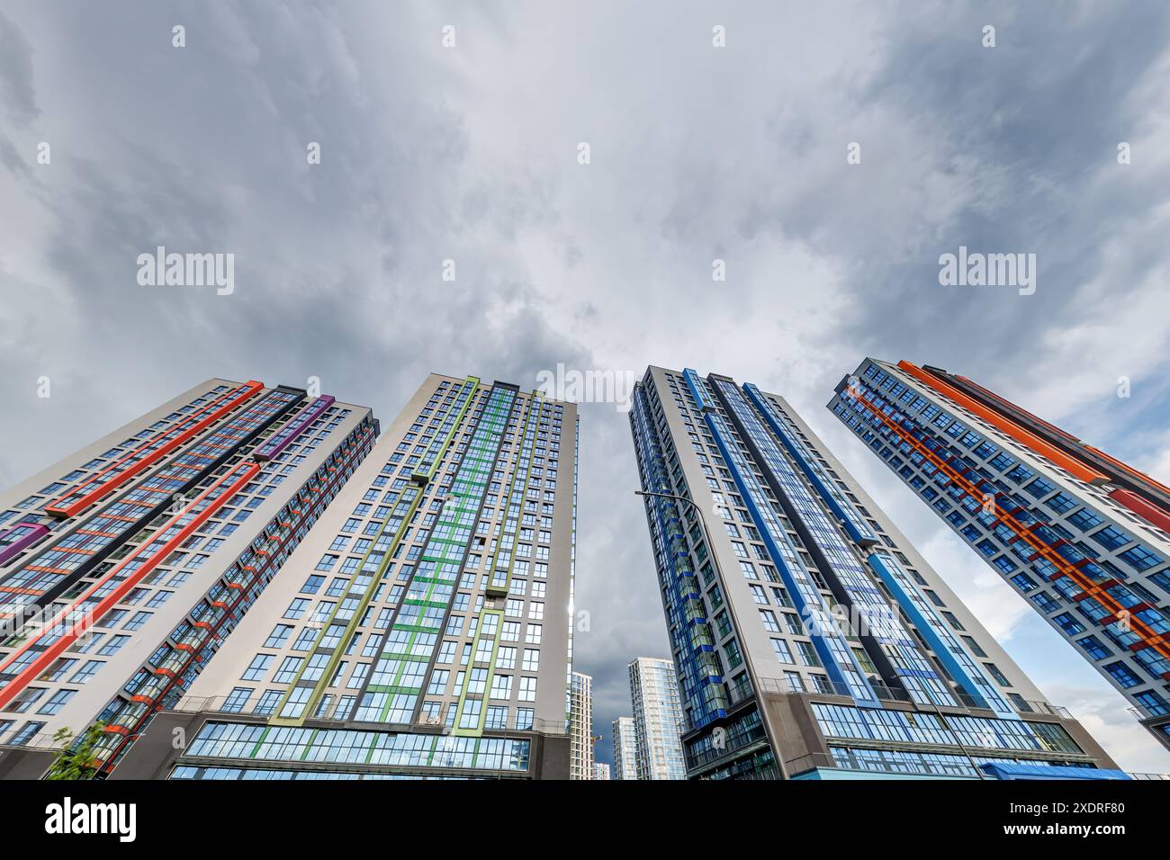 vue d'en bas dans le ciel orageux avec des nuages sombres de grand complexe résidentiel de gratte-ciel moderne Banque D'Images