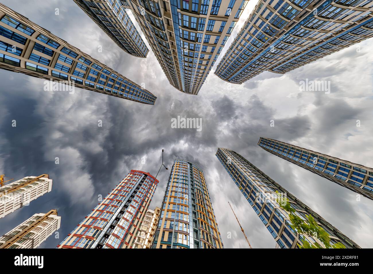 vue d'en bas dans le ciel orageux avec des nuages sombres de grand complexe résidentiel de gratte-ciel moderne Banque D'Images