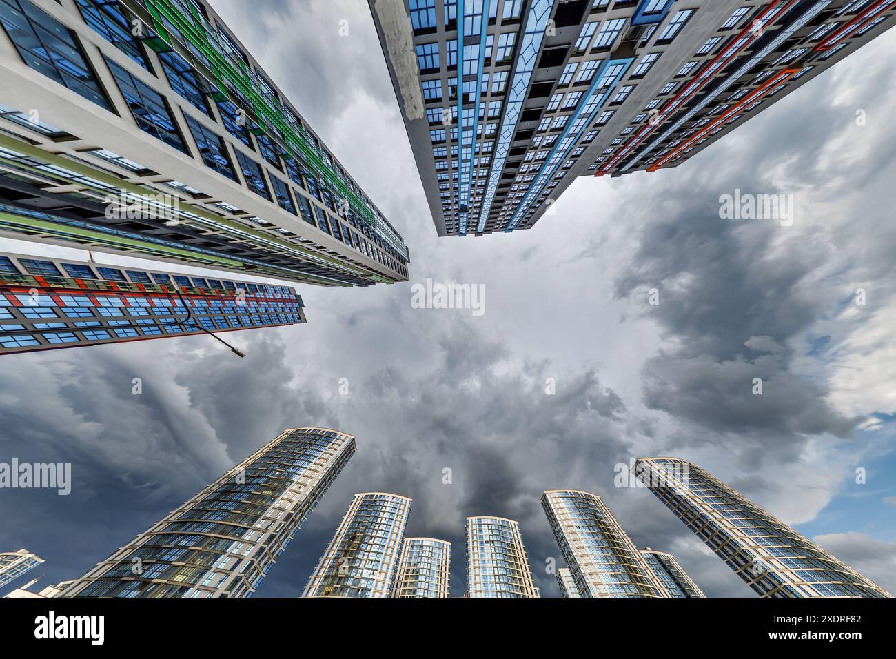 vue d'en bas dans le ciel orageux avec des nuages sombres de grand complexe résidentiel de gratte-ciel moderne Banque D'Images