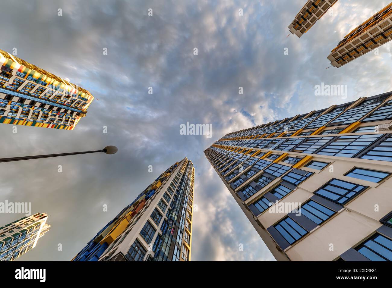 vue d'en bas dans le ciel orageux avec des nuages sombres de grand complexe résidentiel de gratte-ciel moderne Banque D'Images