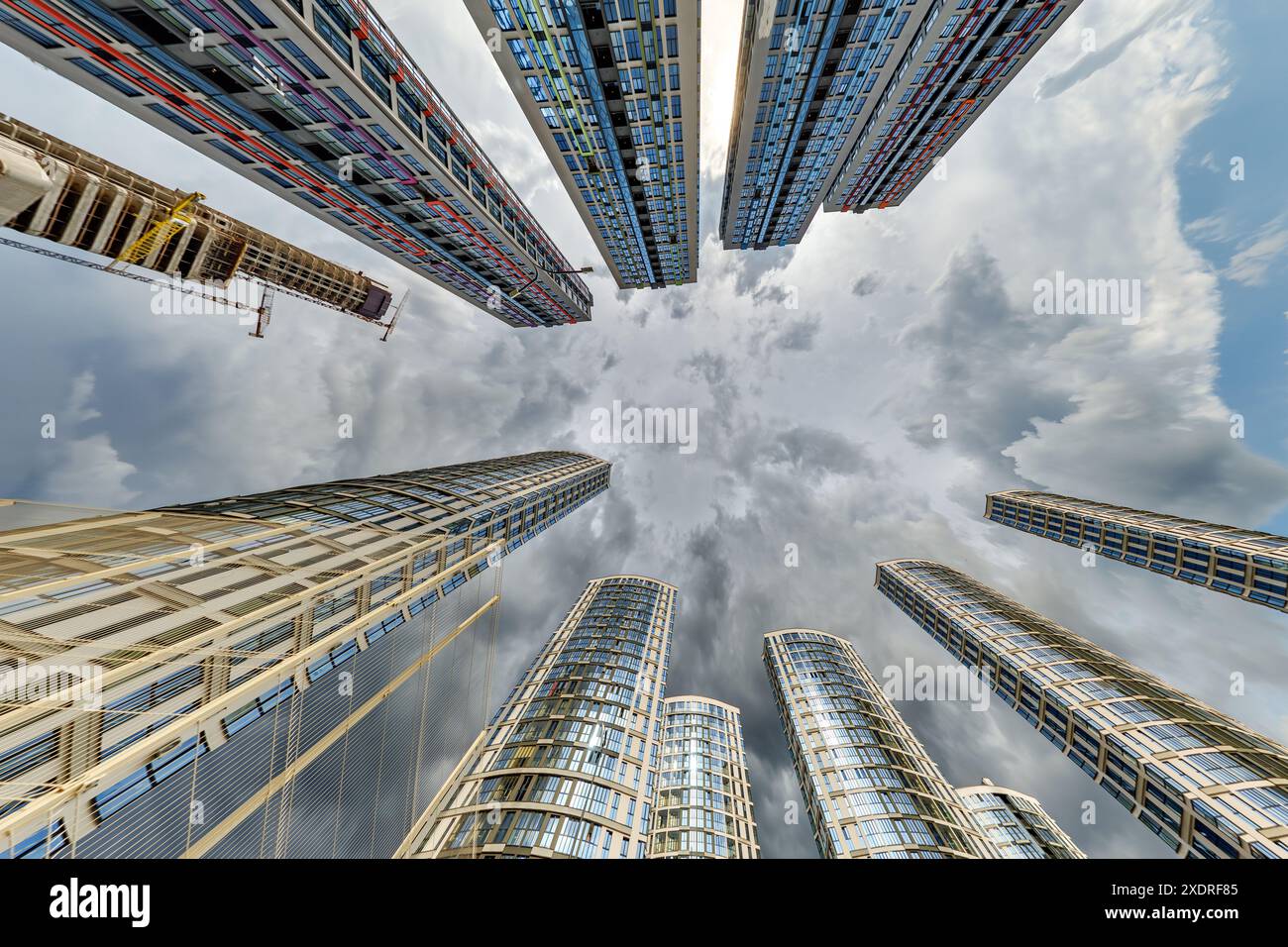 vue d'en bas dans le ciel orageux avec des nuages sombres de grand complexe résidentiel de gratte-ciel moderne Banque D'Images