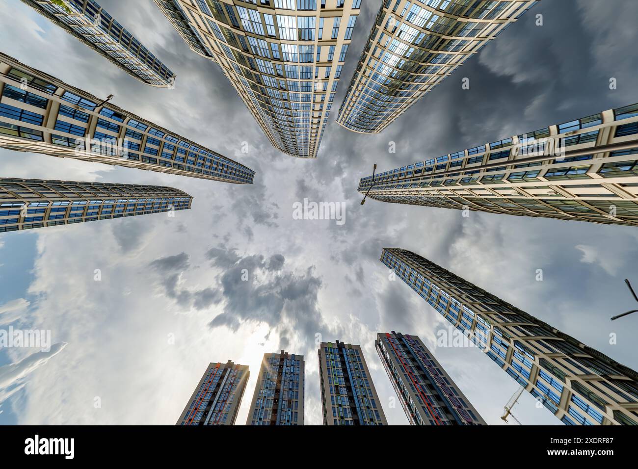 vue d'en bas dans le ciel orageux avec des nuages sombres de grand complexe résidentiel de gratte-ciel moderne Banque D'Images