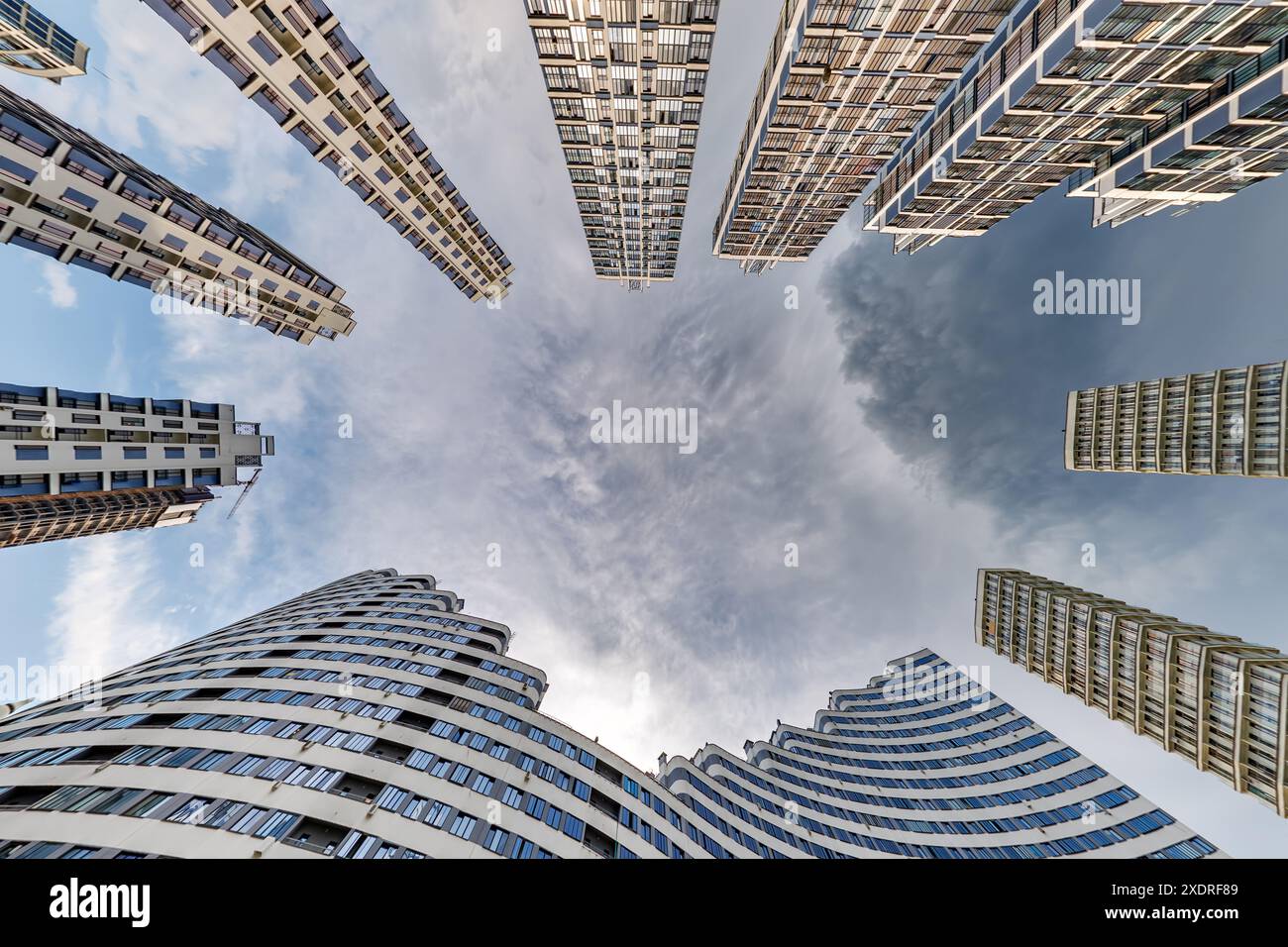 vue d'en bas dans le ciel orageux avec des nuages sombres de grand complexe résidentiel de gratte-ciel moderne Banque D'Images