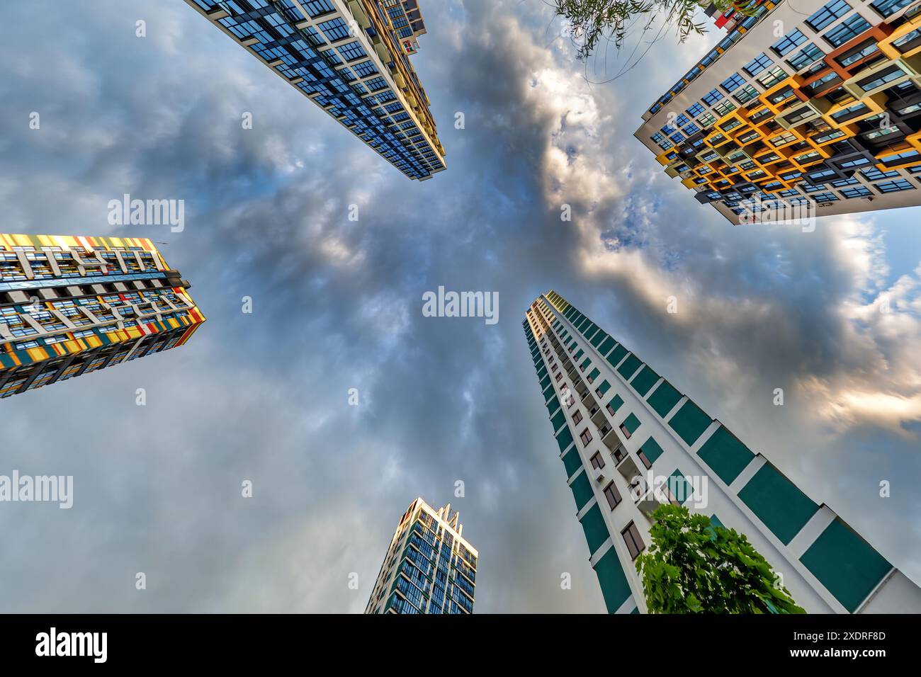 vue d'en bas dans le ciel orageux avec des nuages sombres de grand complexe résidentiel de gratte-ciel moderne Banque D'Images