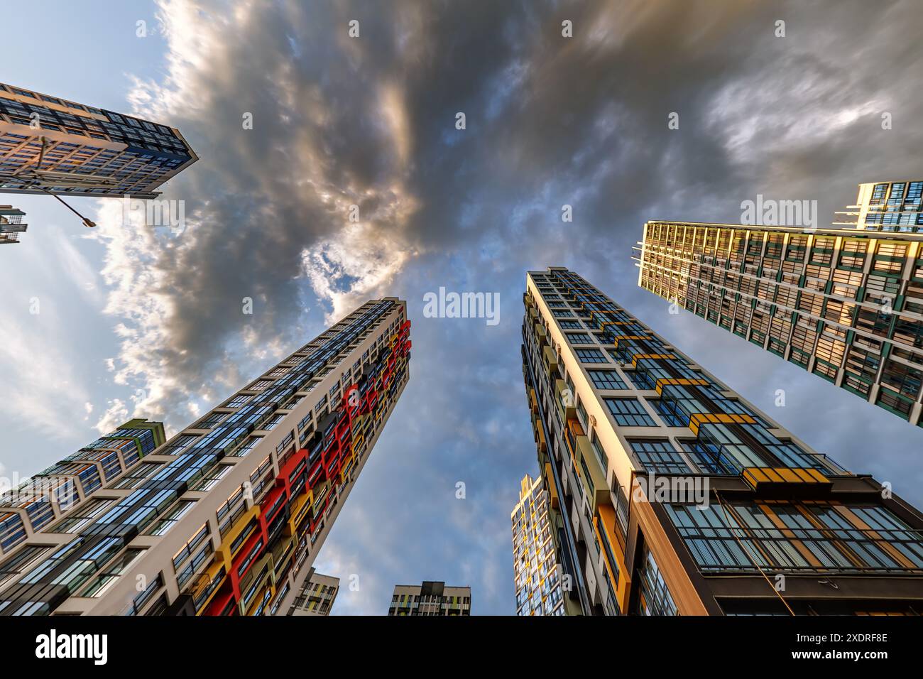 vue d'en bas dans le ciel orageux avec des nuages sombres de grand complexe résidentiel de gratte-ciel moderne Banque D'Images