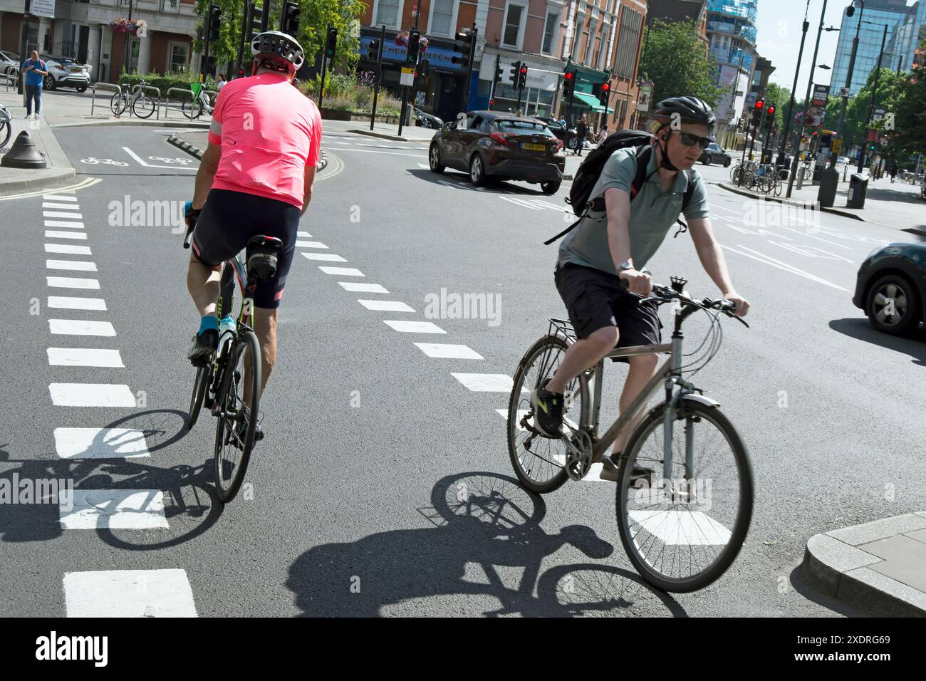 deux cyclistes masculins utilisent des voies cyclables ségréguées bidirectionnelles au giratoire hammersmith, hammersmith, londres, angleterre Banque D'Images