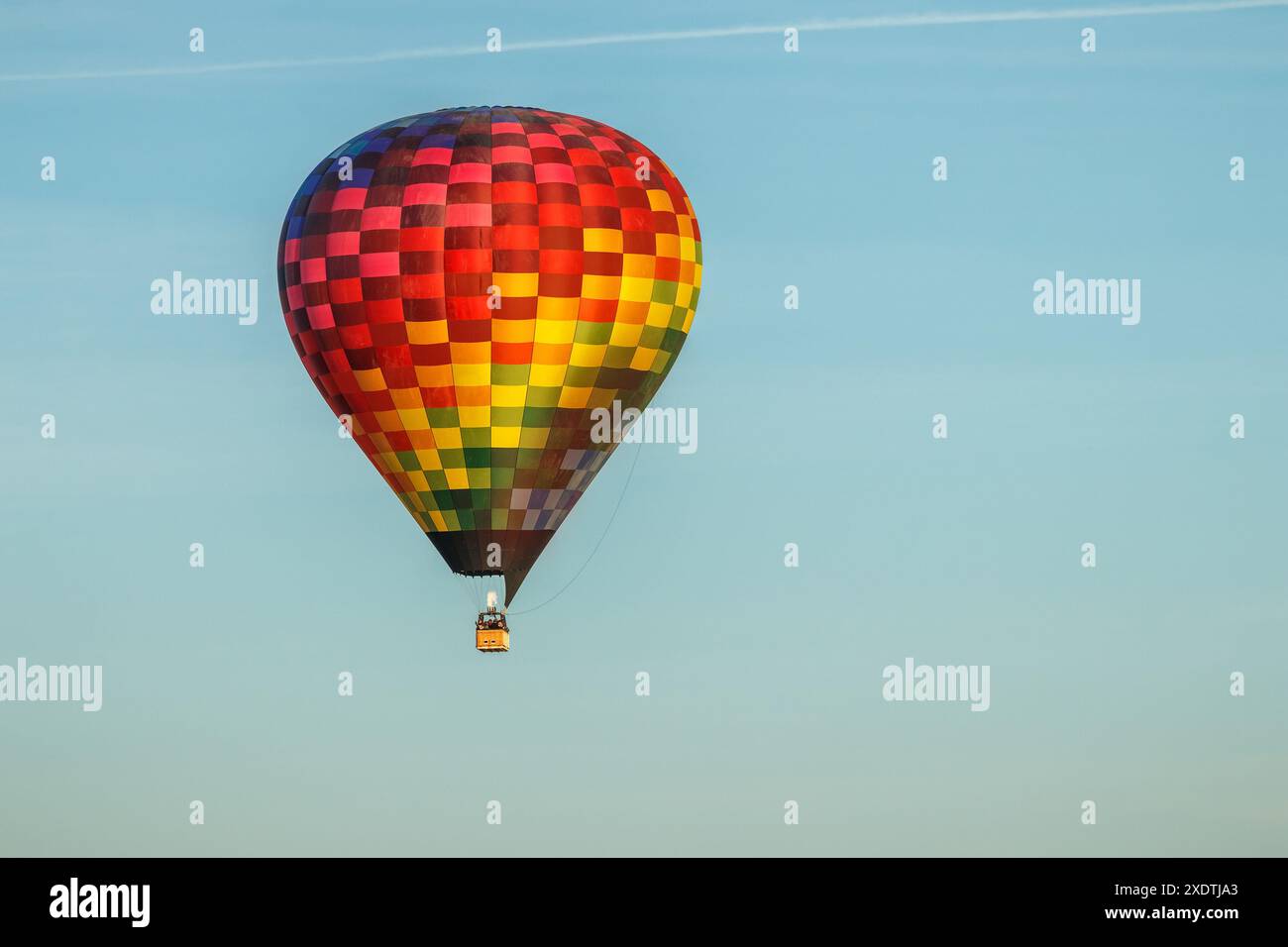 Montgolfière colorée en plein vol avec un ciel bleu en arrière-plan. Banque D'Images