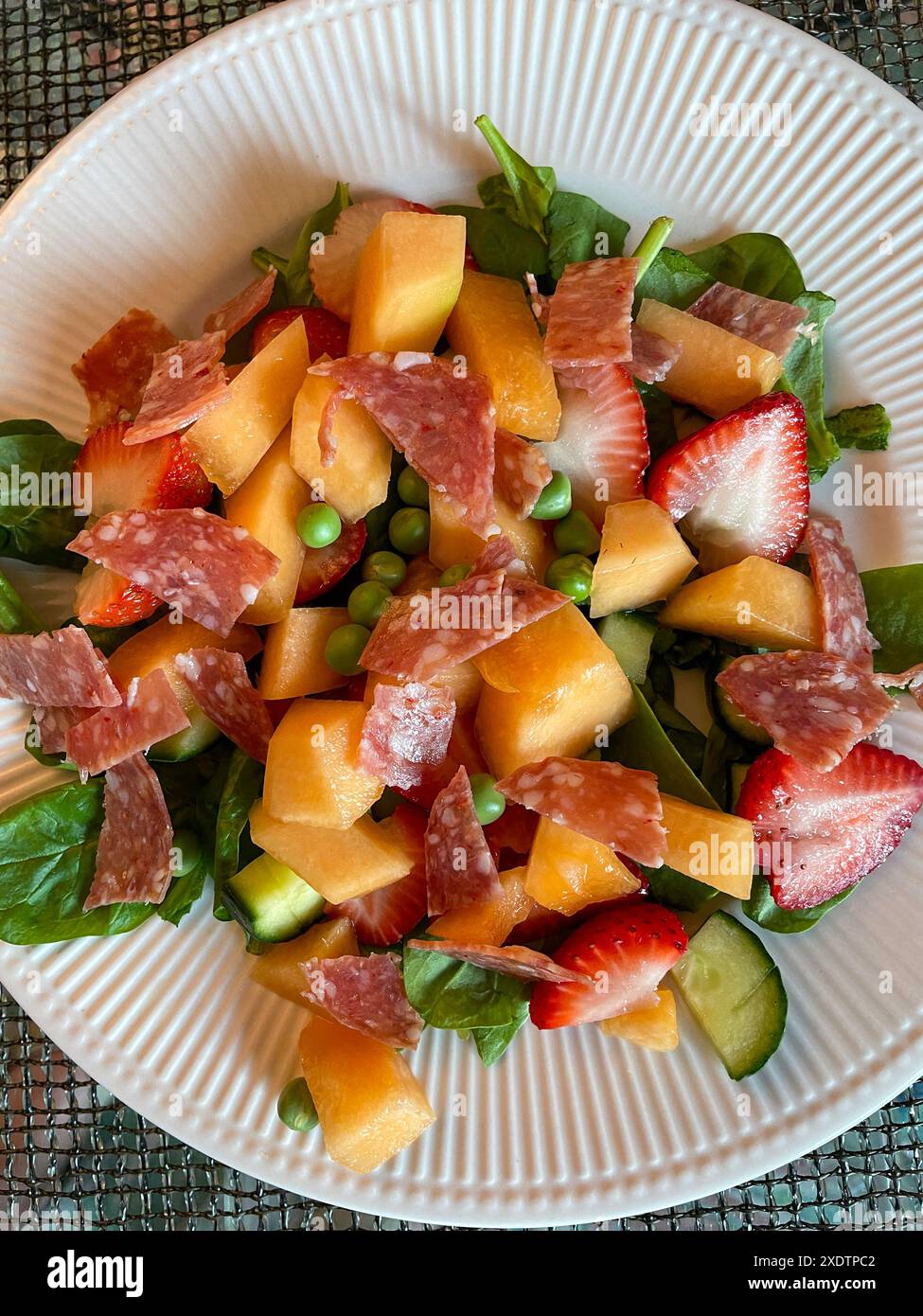Une salade rafraîchissante de plat principal, des caractéristiques, du cantaloup, des fraises et des pois frais du jardin sur un lit d'épinards, 2024, États-Unis Banque D'Images