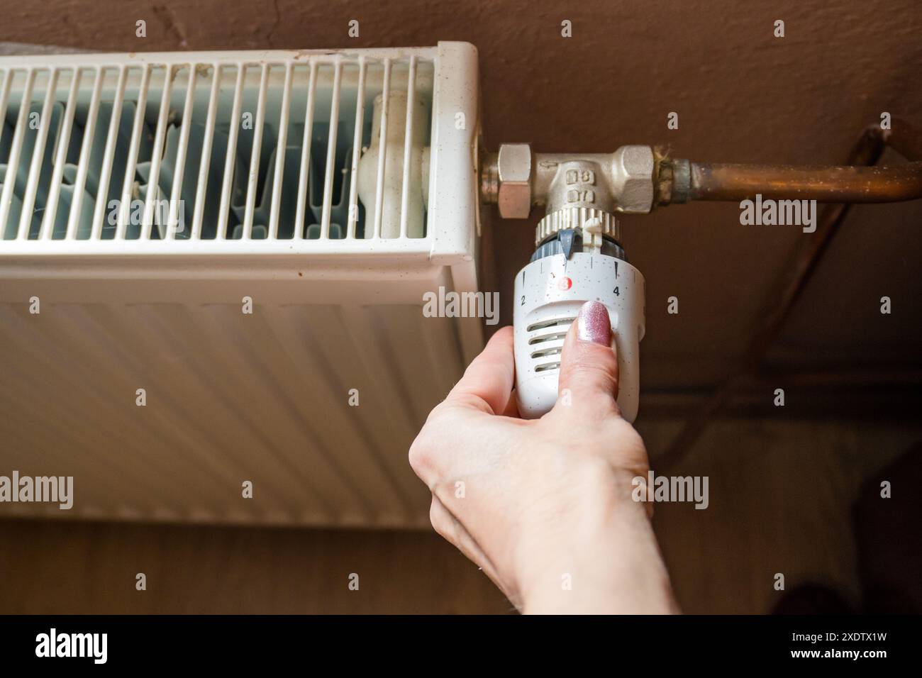 Réglage manuel de la température sur le thermostat du radiateur de chauffage, concept économique. Tourner le bouton du radiateur de chauffage pour contrôler la chaleur dans la maison. Augmentant ou diminuant Banque D'Images