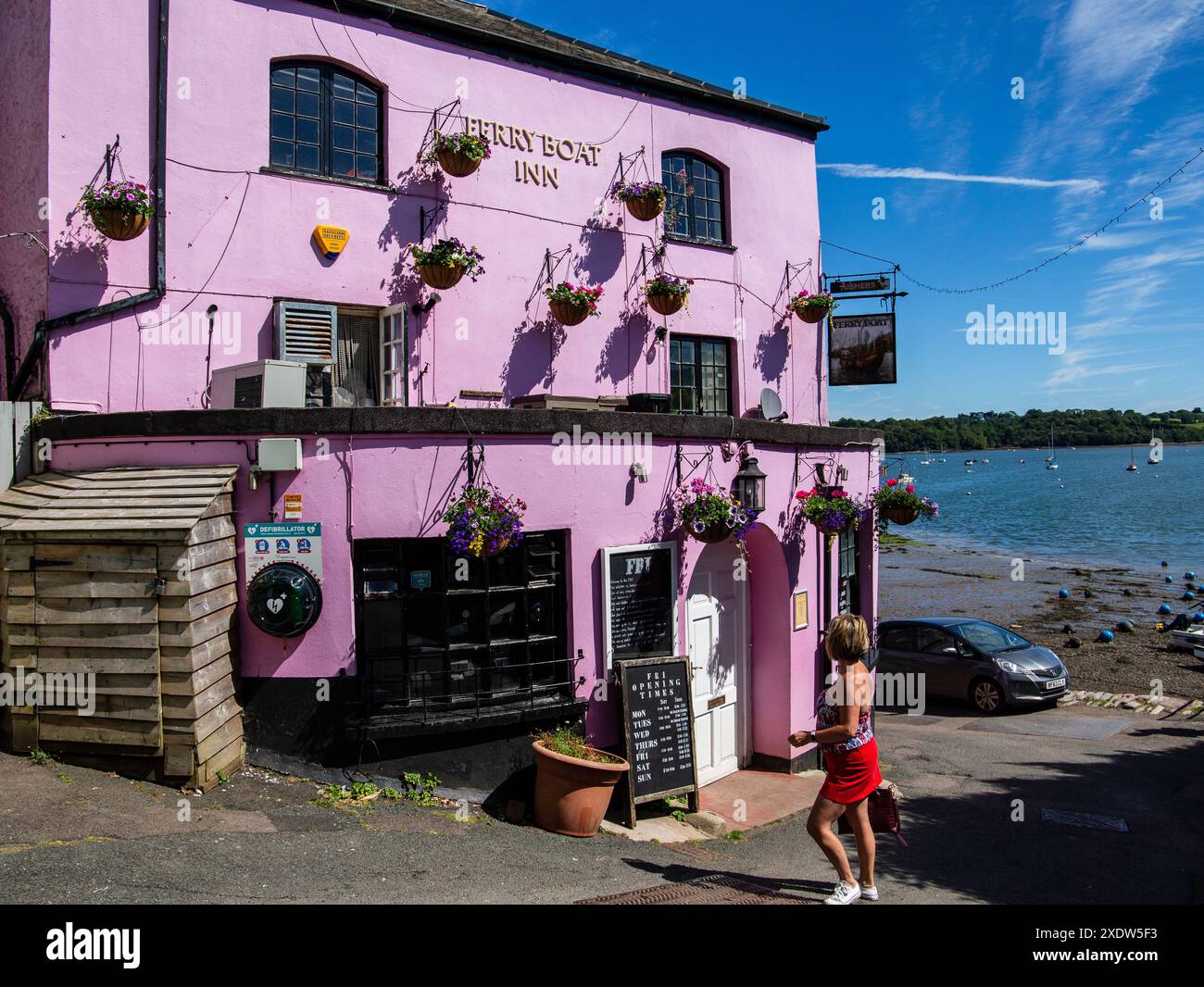 Personne marchant dans un pub violet dynamique le Ferry Boat Inn Dittisham Devon UK près du front de mer sous un ciel bleu clair Banque D'Images