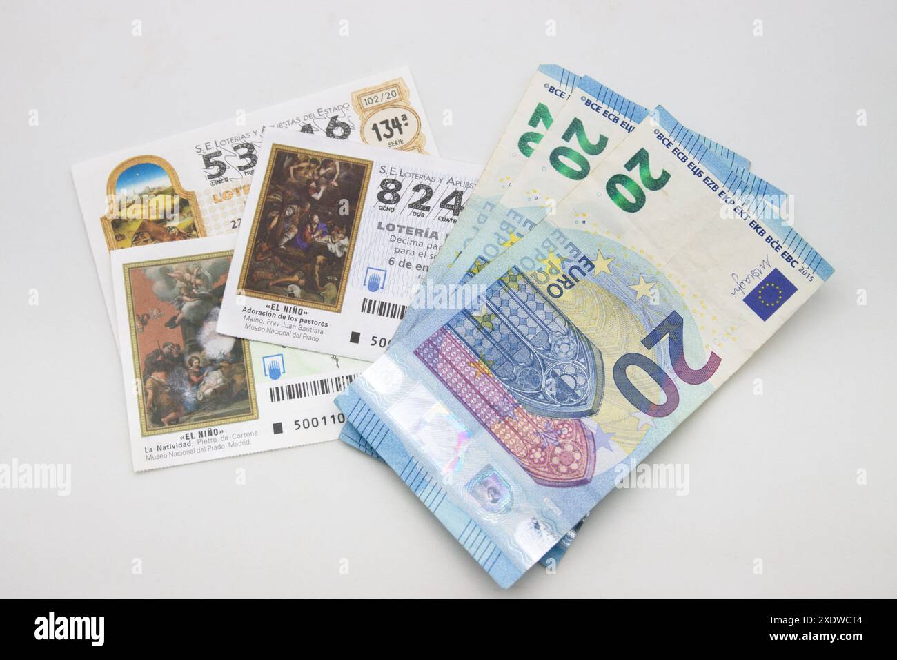Plat de quelques billets de loterie nationale en Espagne pour le tirage El Niño, en janvier, à côté de billets de 20 € sur fond blanc Banque D'Images