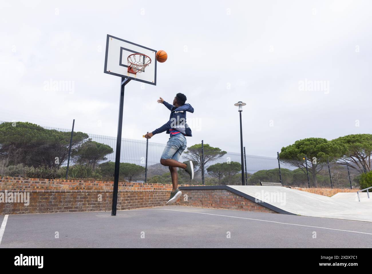 Jouer au basket-ball, adolescent sautant à dunk ball sur le terrain extérieur, espace copie Banque D'Images