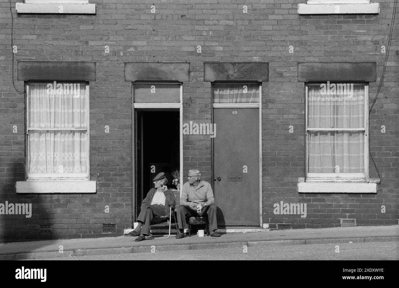 Village de puits communauté minière de charbon Yorkshire années 1970 Nord de l'Angleterre. Deux mineurs sur leur jour de congé, assis à l'extérieur de leurs maisons mitoyennes sur le trottoir profitant d'un homme au soleil. South Kirkby, Yorkshire Angleterre 1979. ANNÉES 1970 ROYAUME-UNI HOMER SYKES Banque D'Images