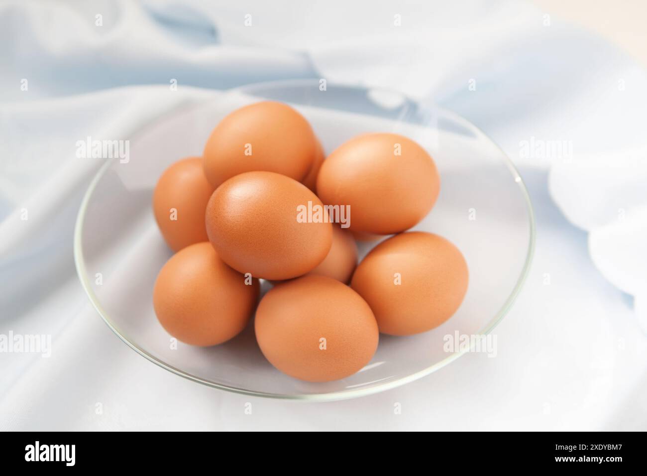 Oeufs de poules dans la plaque de verre sur la nappe bleu clair Banque D'Images