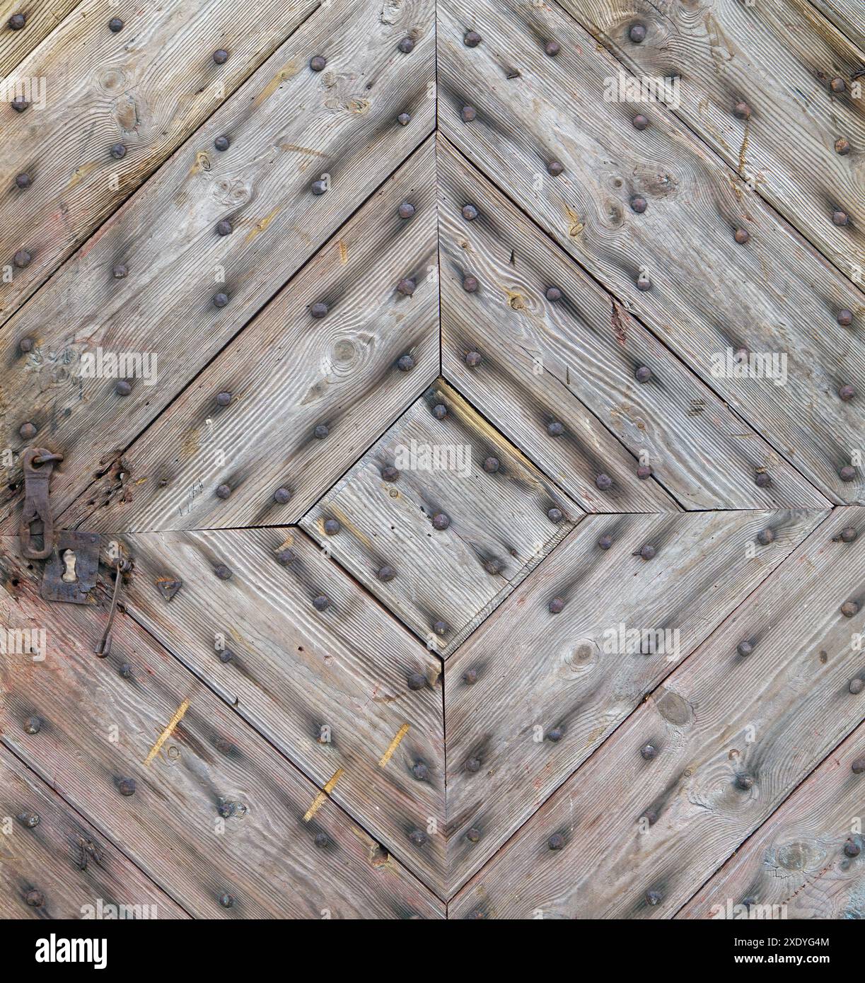 La porte de l'ancienne maison de campagne est faite de planches diagonales et de clous rouillés Banque D'Images