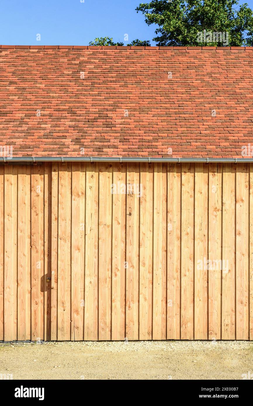 Nouveau bâtiment de stockage agricole revêtu de bois avec porte coulissante en bois - Boussay, Indre-et-Loire (37), France. Banque D'Images