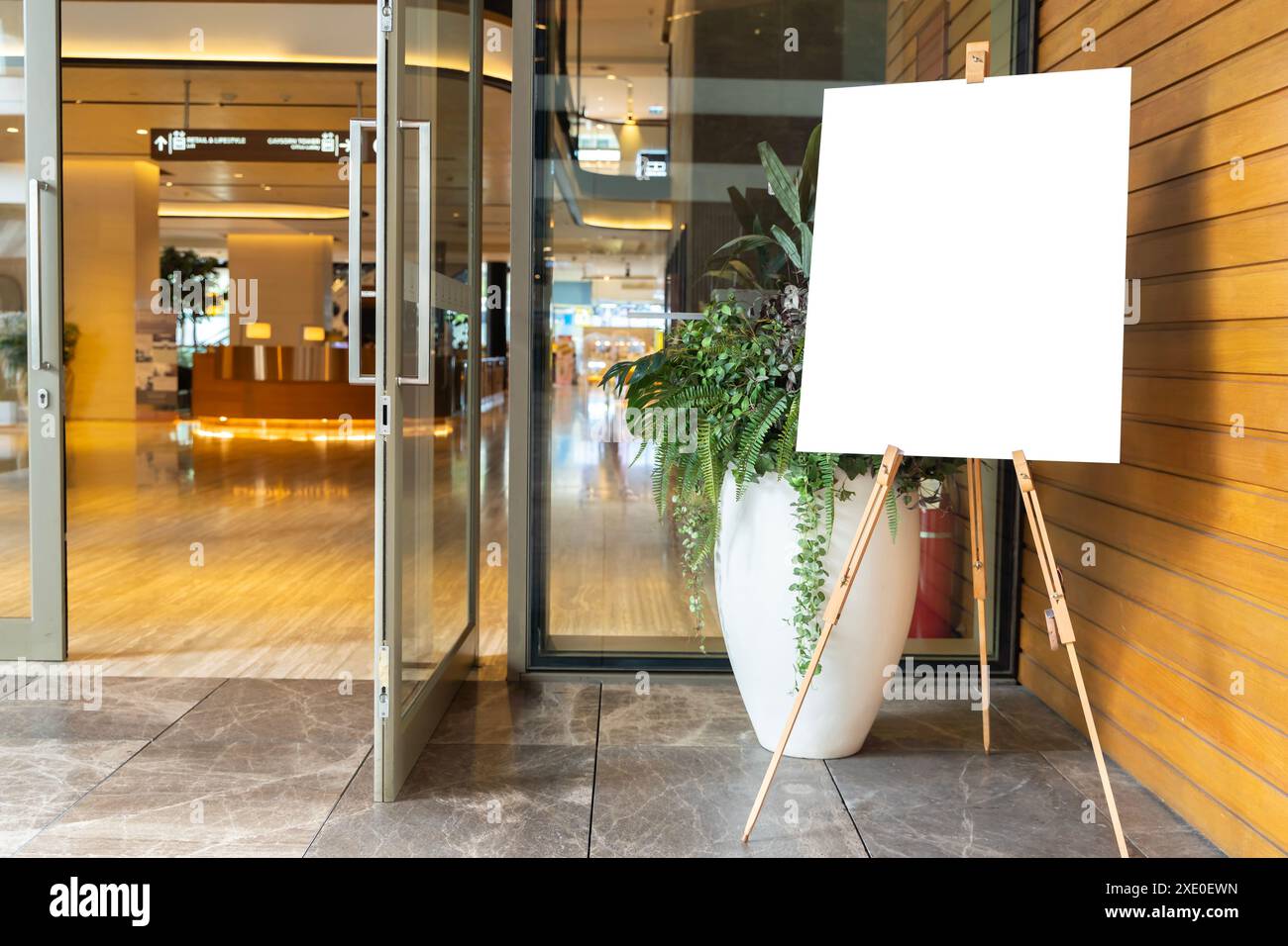 Photo d'une toile blanche vierge sur le chevalet d'un artiste dans un studio. La toile est orientée verticalement et est légèrement décentrée dans le cadre. Le Banque D'Images