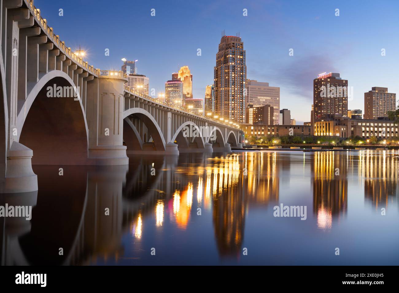 Minneapolis, Minnesota, USA ligne d'horizon du centre-ville sur le fleuve Mississippi avec le pont de la troisième Avenue au crépuscule. Banque D'Images