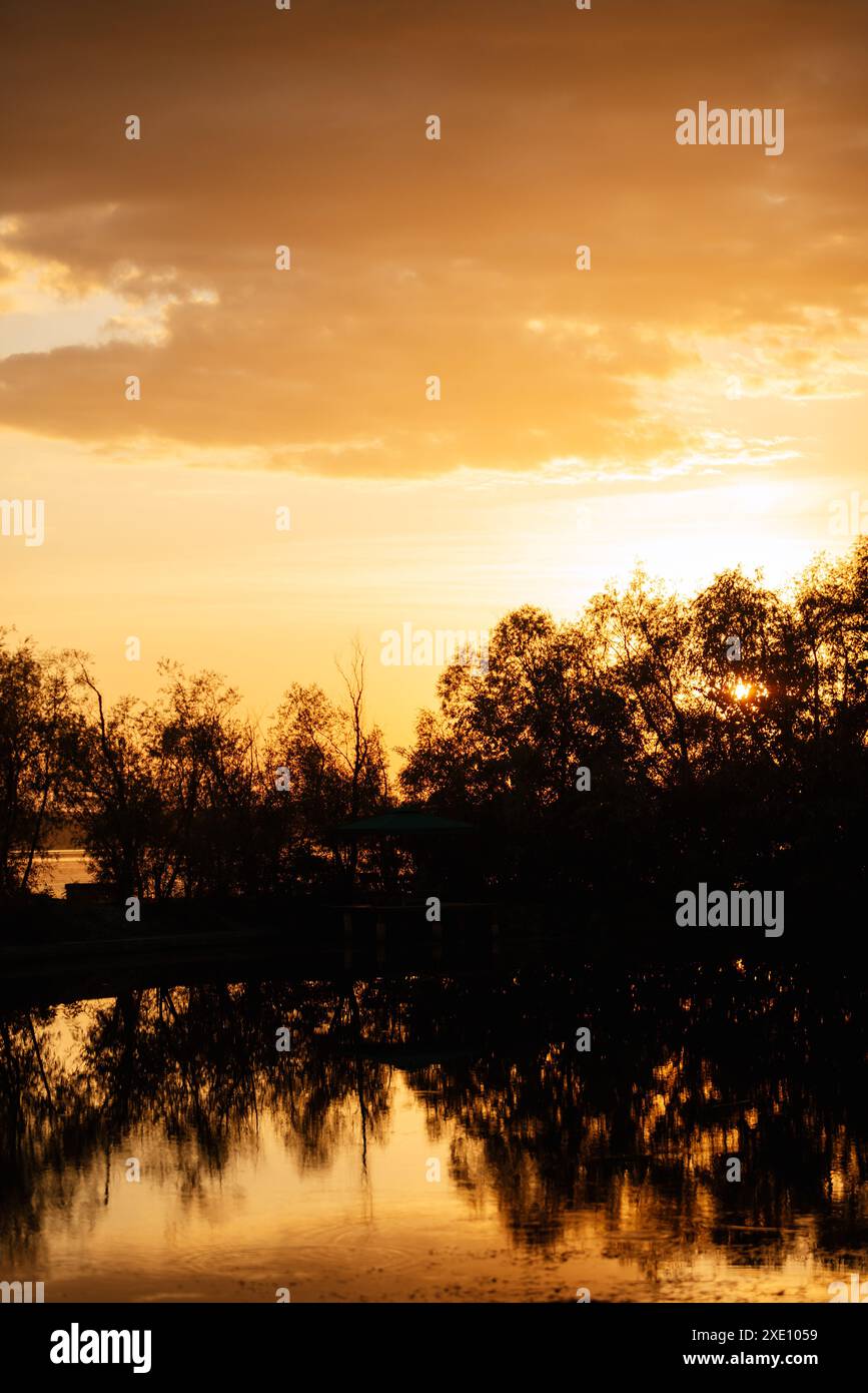 Coucher de soleil orange sur la rivière avec des silhouettes Banque D'Images