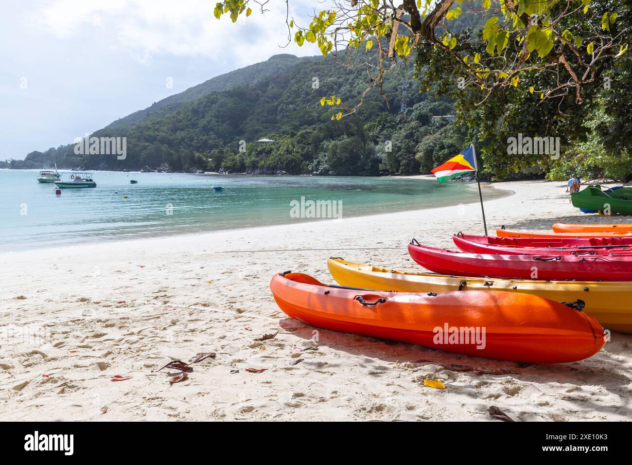 Des kayaks en plastique rouge gisaient sur la côte. Paysage de plage d'été avec drapeau des Seychelles par une journée ensoleillée Banque D'Images