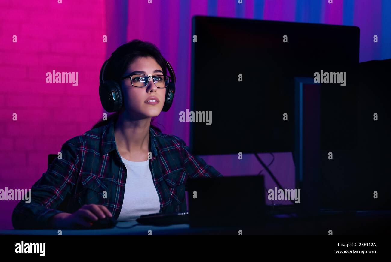 Jeune femme portant des lunettes et des écouteurs utilise un ordinateur Banque D'Images