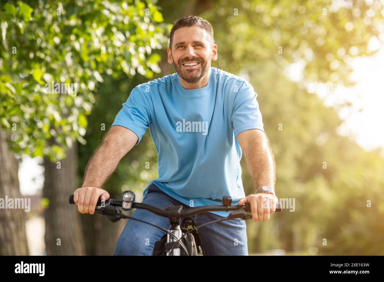 Happy Man Riding Bicycle le jour d'été ensoleillé dans le parc Banque D'Images