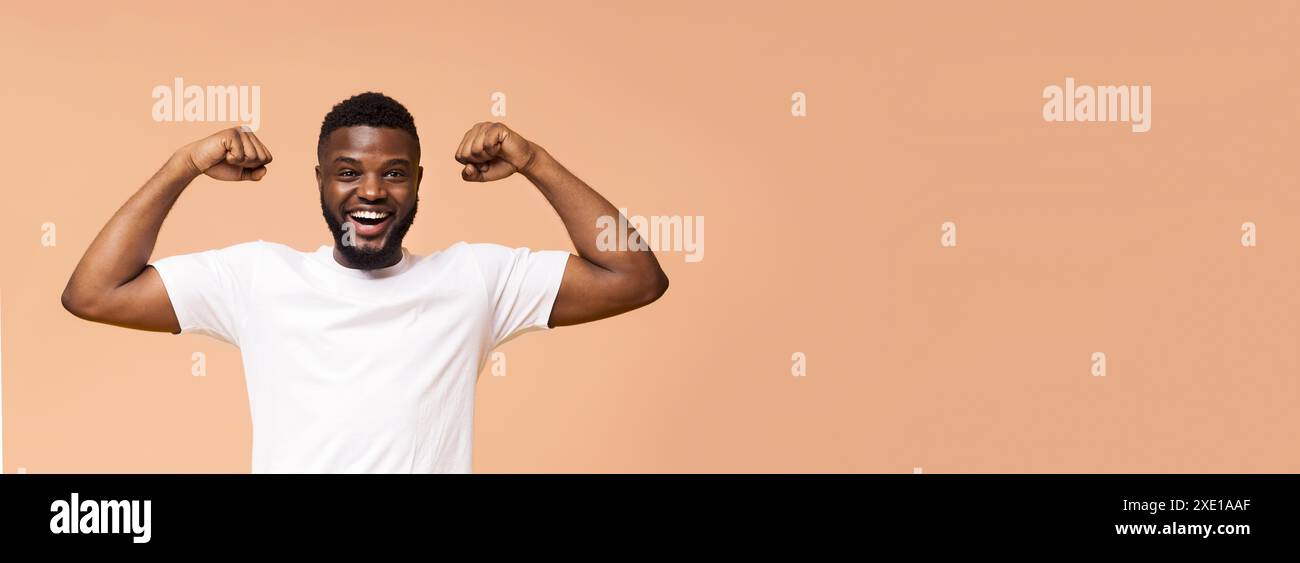 Happy Man Flexing muscles devant Un fond beige Banque D'Images