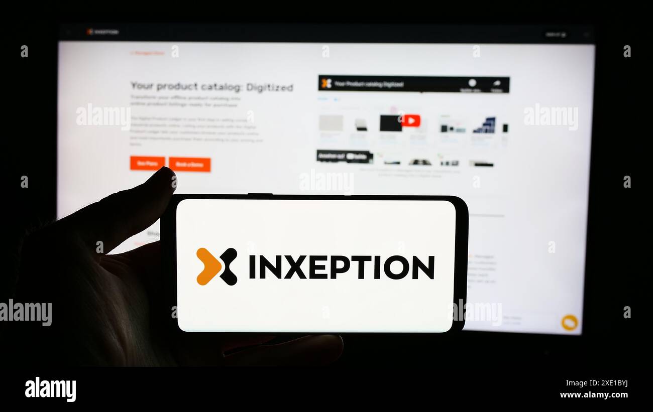 Personne tenant le téléphone portable avec le logo de la société de plate-forme de commerce électronique américaine Inxeption Corporation devant la page Web de l'entreprise. Concentrez-vous sur l'affichage du téléphone. Banque D'Images