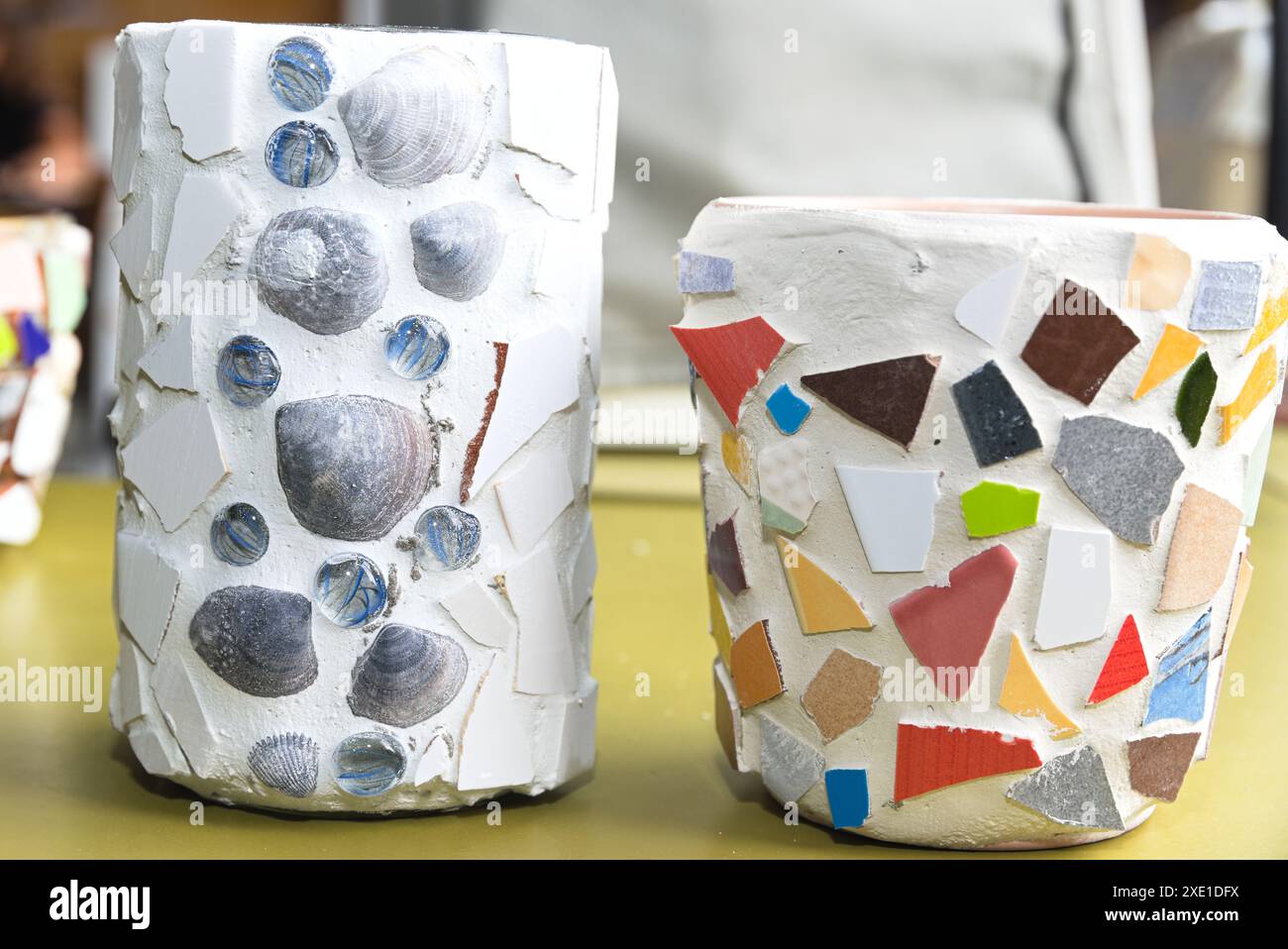 Mosaïque avec des parties de tuiles et des coquillages sur un pot de fleurs et une jardinière Banque D'Images