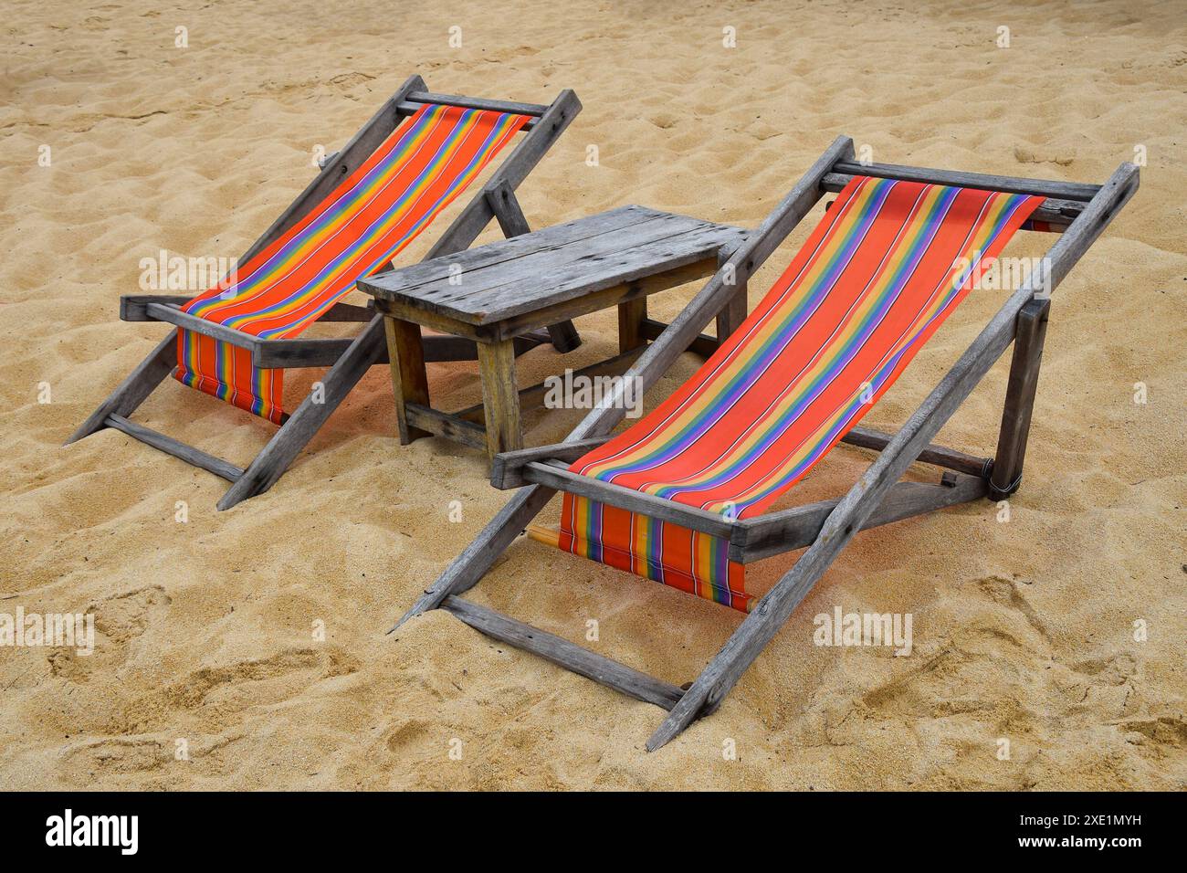 Deux chaises longues en bois colorées sur la plage de sable Banque D'Images