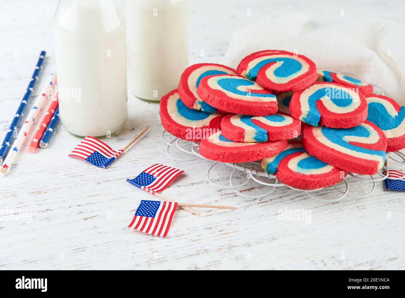 4 juillet arrière-plan des vacances. Biscuits au sucre rouge blanc et bleu Pinwheel avec verre de lait pour la célébration du 4 juillet sur vieux fond de bois blanc. Pat Banque D'Images