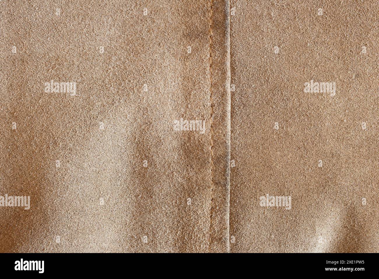 Gros plan d’un tissu texturé beige avec couture verticale, mettant en valeur sa surface fine et douce et ses coutures précises, met en valeur la texture luxueuse du tissu Banque D'Images