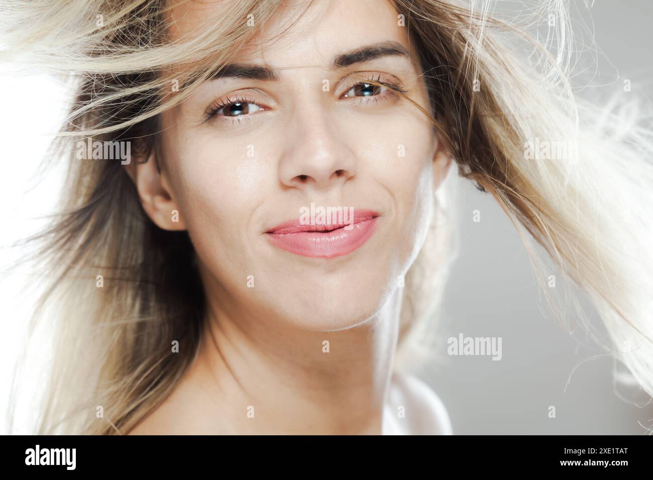 Un portrait en gros plan vibrant d'une femme caucasienne avec son doux sourire et ses cheveux blonds fluides déplacés par le vent. Banque D'Images