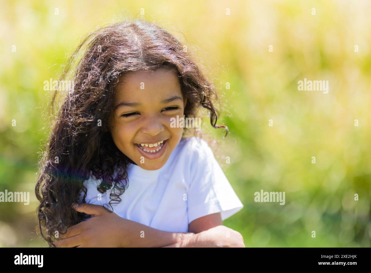 Petite fille mulâtre dans un T-shirt blanc sur une promenade d'été. Photo de haute qualité Banque D'Images