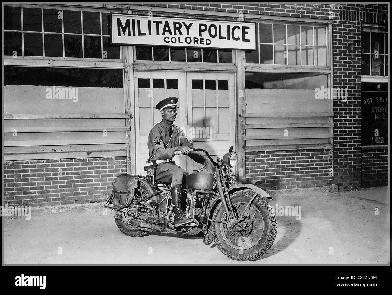 1940s/50s SÉGRÉGATION RACIALE EMPLOI MILITAIRE USA photographie promotionnelle montre un député sur une moto prêt à répondre aux appels dans sa région de Columbus Georgia. Un signe raciste discriminatoire derrière lui désigne LA POLICE MILITAIRE colorée. Géorgie États-Unis Banque D'Images