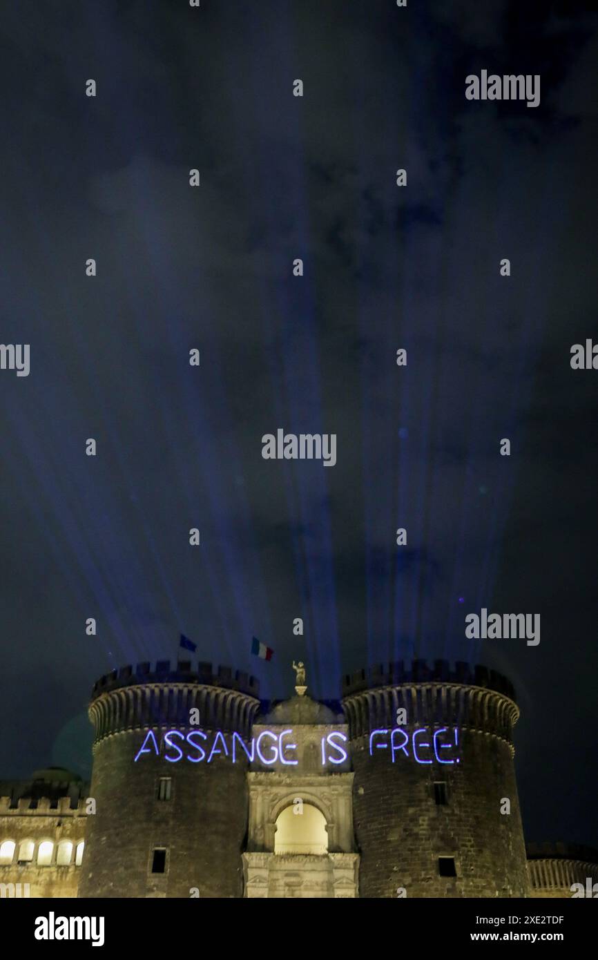 Naples : un groupe de militants libres de Julian Assange se réunit devant le château de Malé Angioino, projetant Assange est libre sur la façade pour célébrer et porter un toast après sa libération Banque D'Images