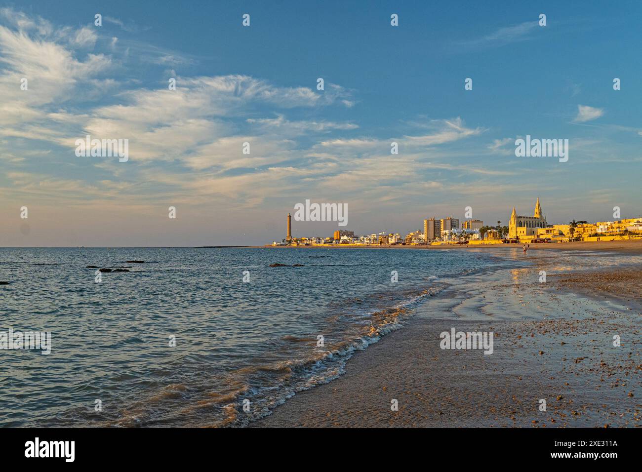 Plage de Regla avec église et phare à Chipiona dans la lumière chaude du soir Banque D'Images