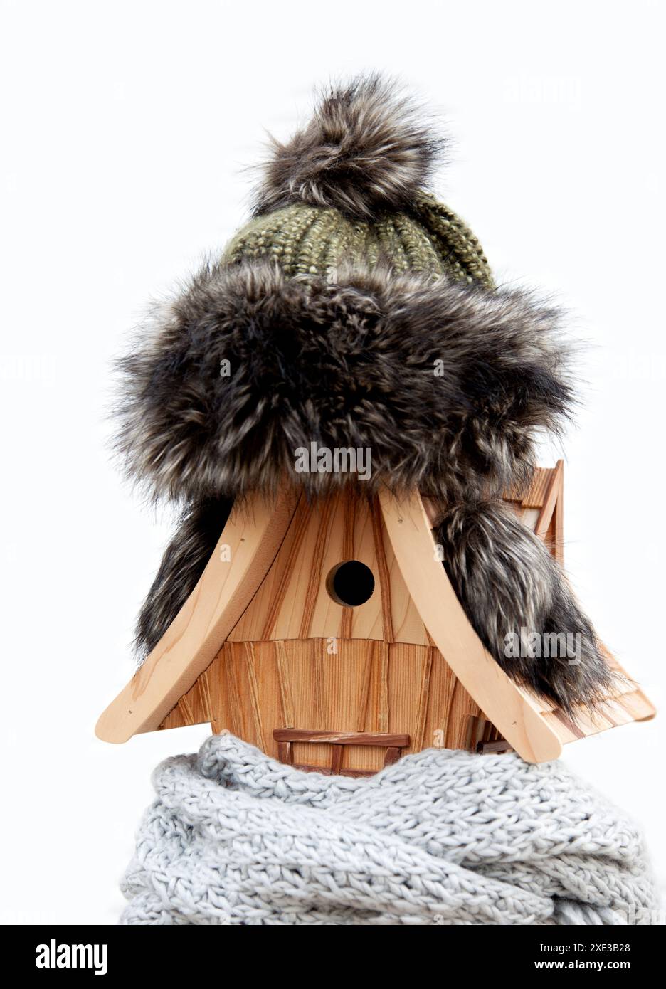 Birdhouse fait à la main en hiver, portant un bonnet tricoté et une écharpe. fond froid de temps neigeux. Banque D'Images