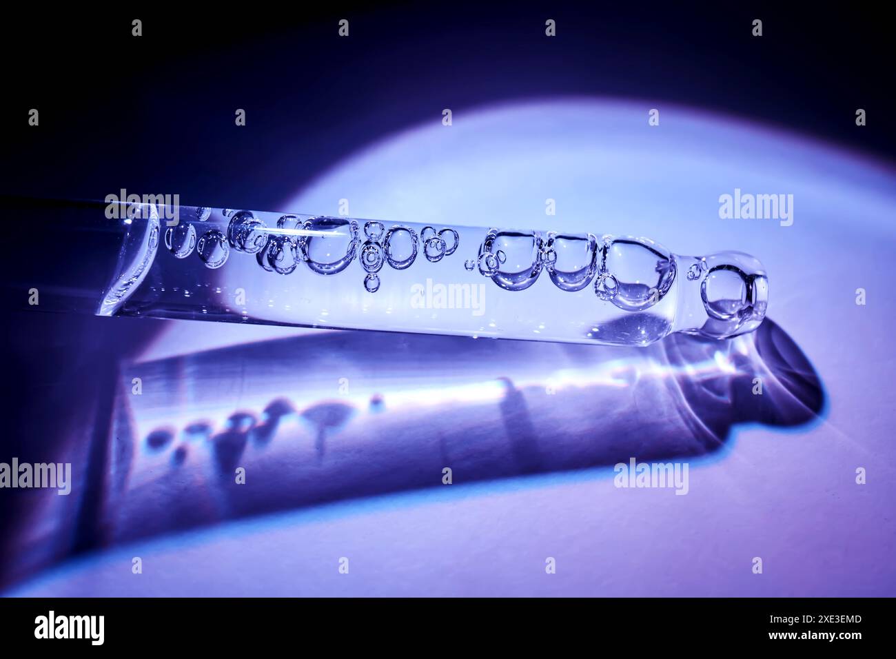 Pipette avec sérum pour le visage à la frontière de la lumière et de l'ombre. Banque D'Images