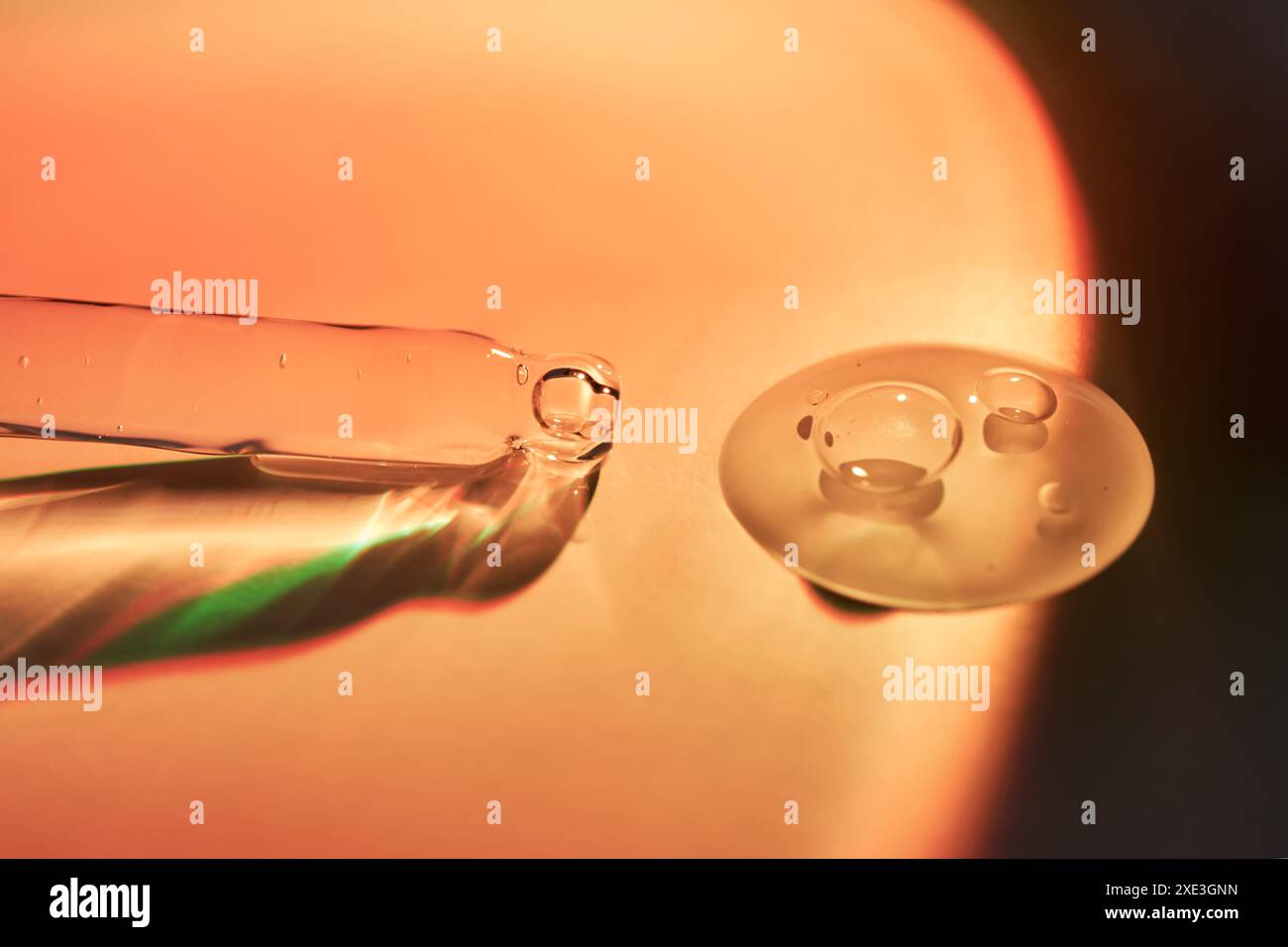 Un compte-gouttes et une goutte de sérum corporel de protection solaire dans la lumière orange du coucher du soleil. Banque D'Images