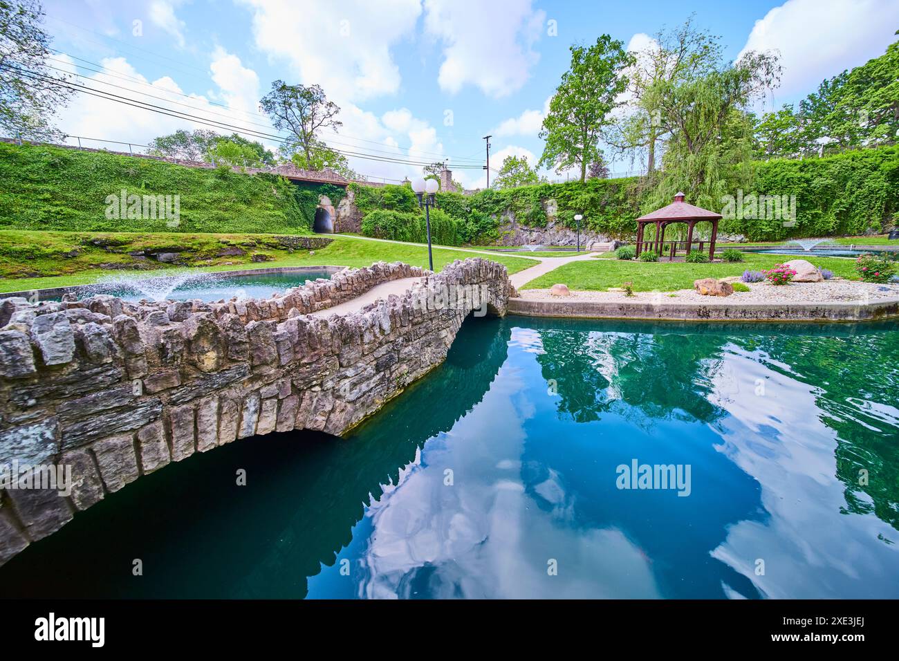 Pont de pierre serein et belvédère près de l'étang réfléchissant dans Sunken Gardens Banque D'Images