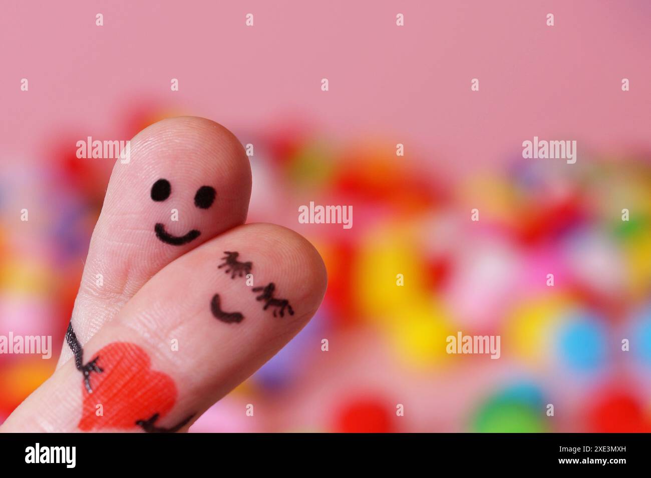 Saint Valentin, couple heureux amoureux. 2 doigts tenant le coeur rouge tout en souriant visage avec multicolo Banque D'Images