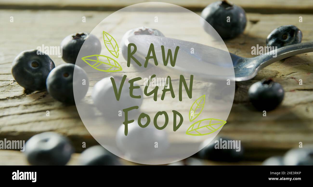 Image de la bannière de texte de nourriture végétalienne crue contre gros plan de baies bleues et cuillère sur la table en bois Banque D'Images