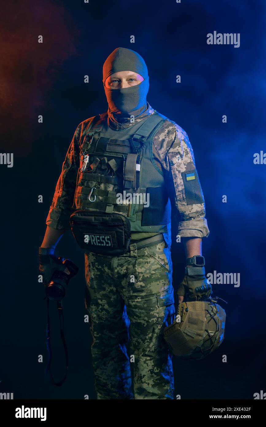 Journaliste militaire en uniforme tactique avec une caméra dans les mains sur fond sombre, journaliste en uniforme militaire Banque D'Images